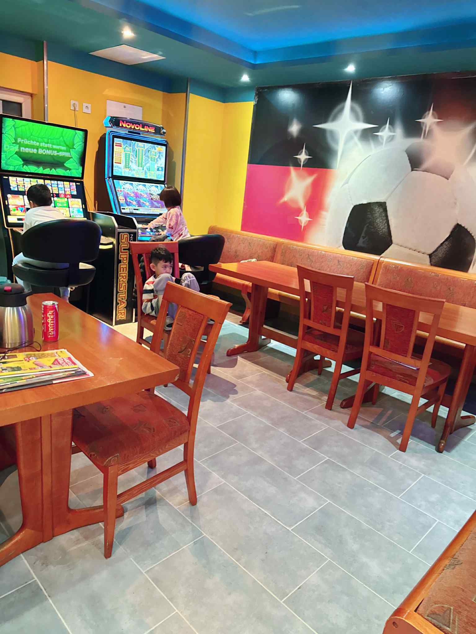 Unterhaltungsbereich mit Spielautomaten, Holztischen und künstlerischer Wandgestaltung